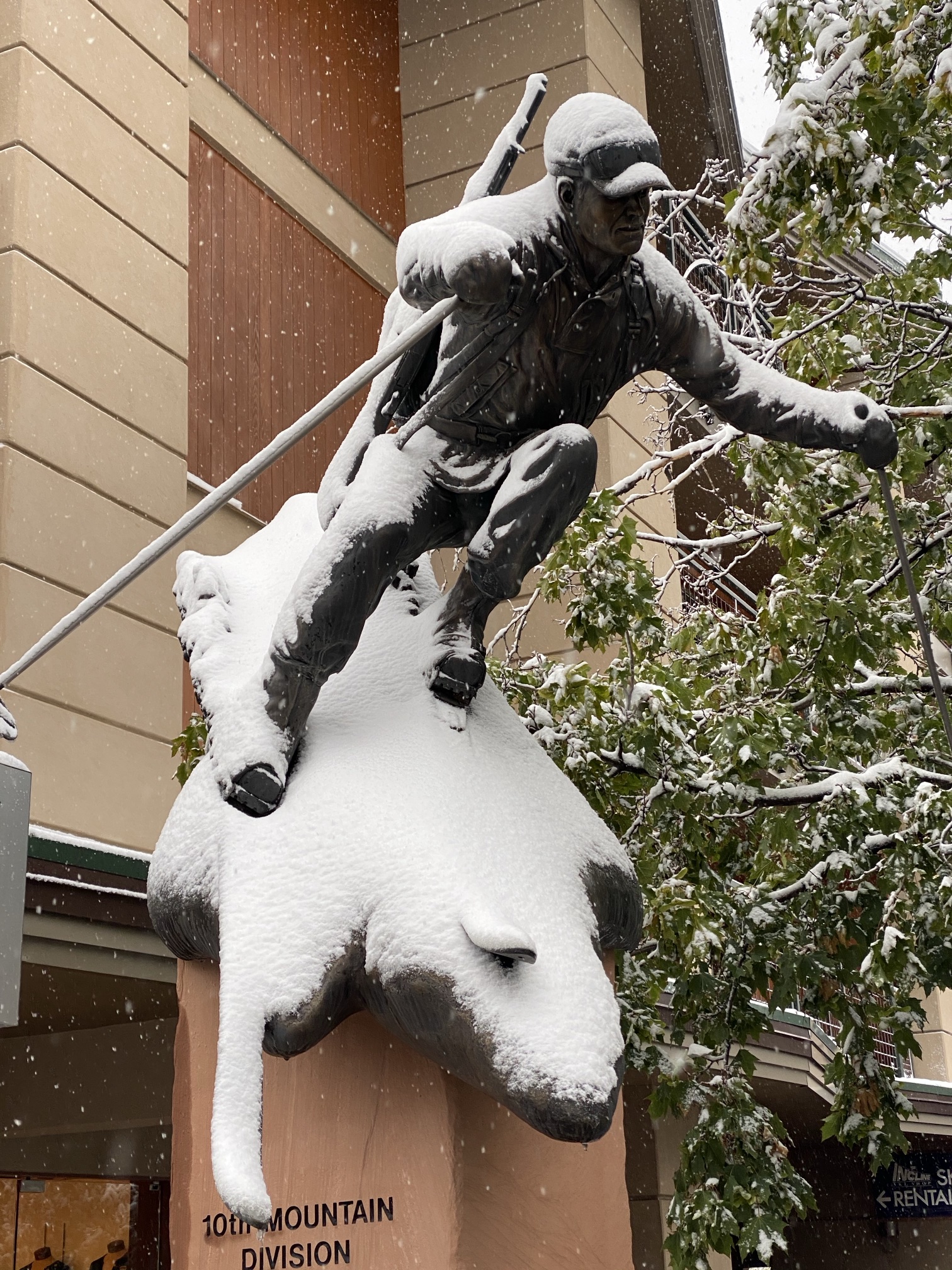 A bronze statue of a 10th Mountain Division ski soldier, rifle on his back, covered in fresh snow