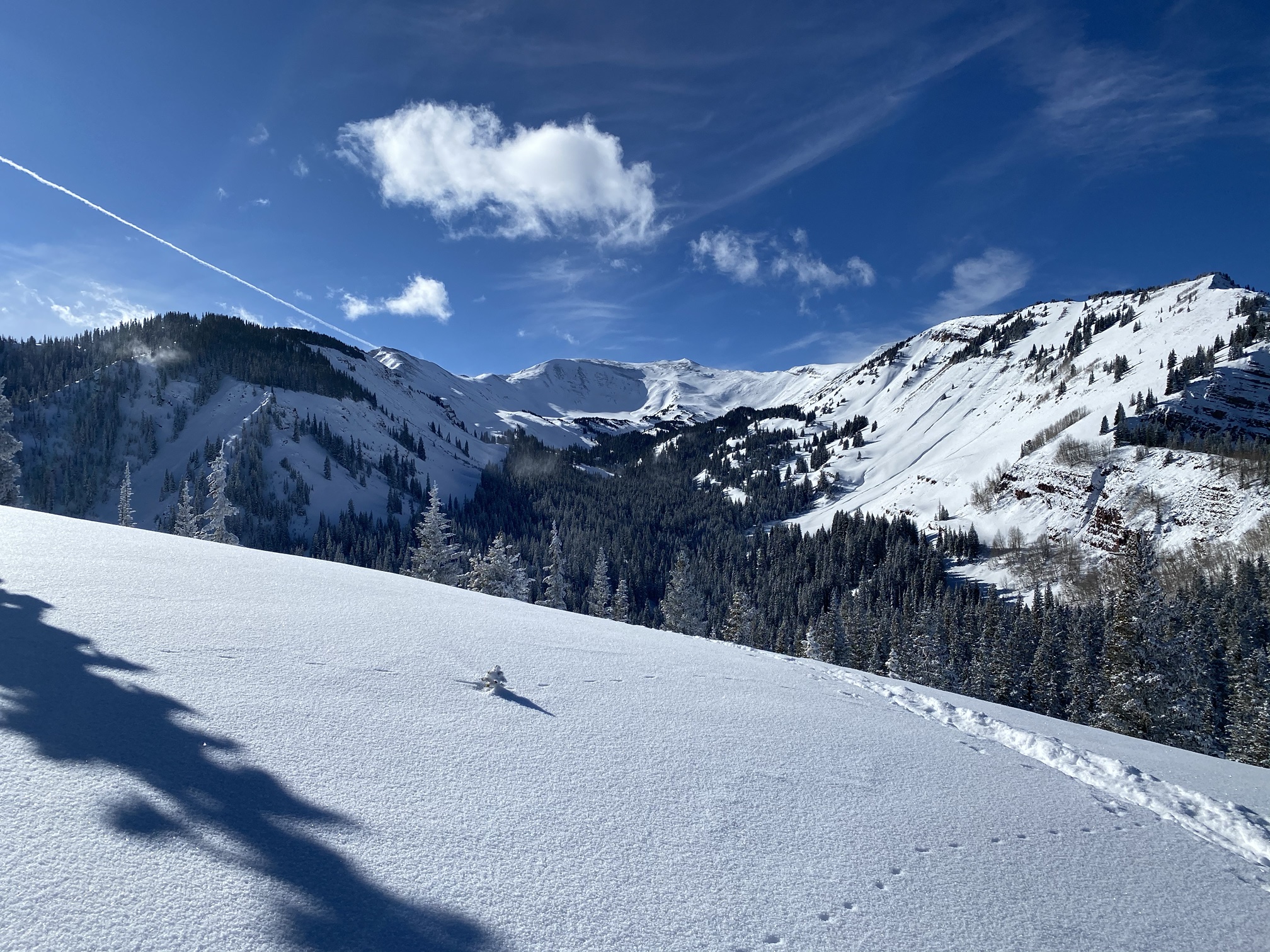 Untracked snow and nearby peaks under a deep blue sky, seen from Snowmass Mountain