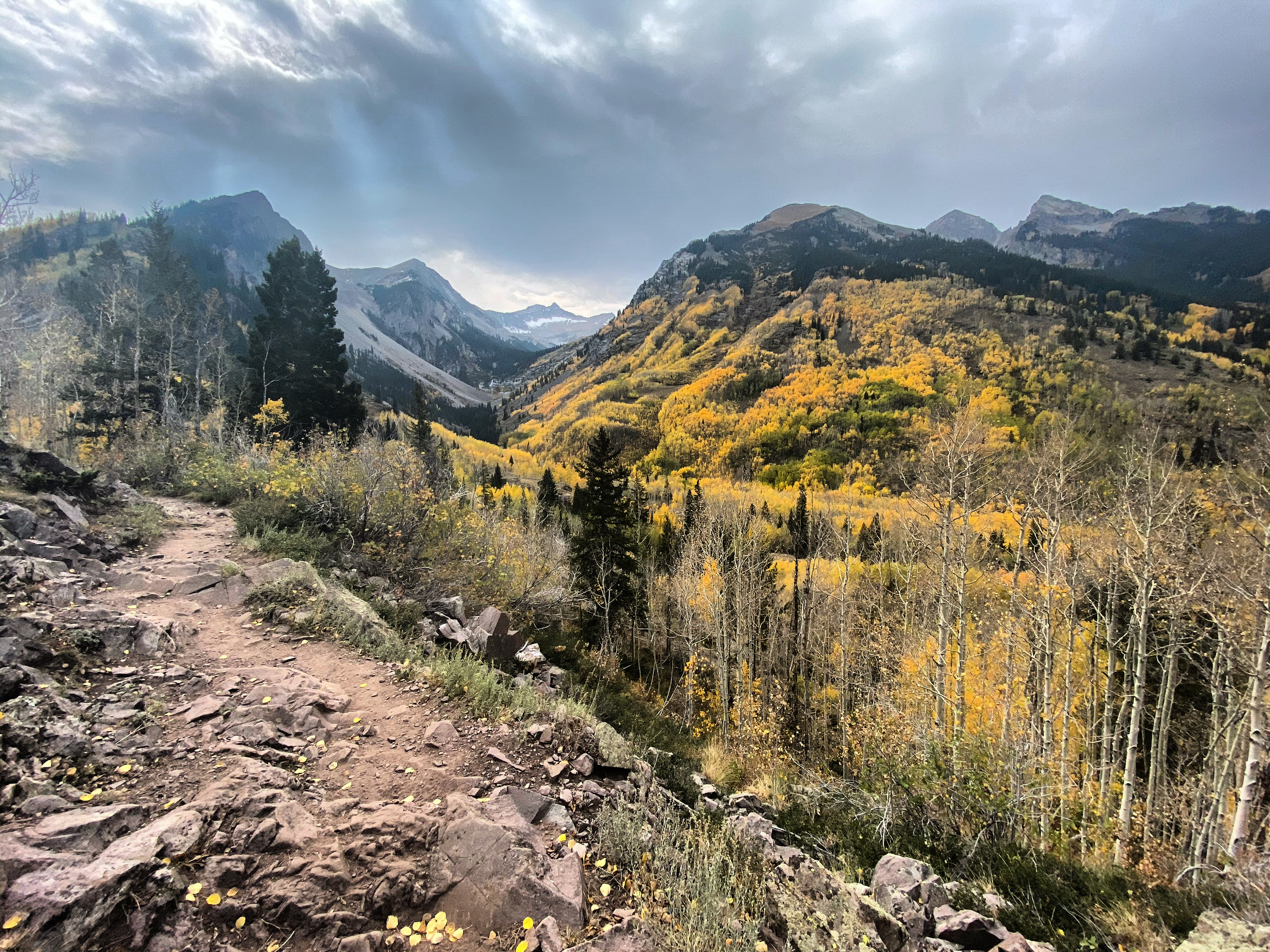 A rocky trail above a valley of golden aspens in the Maroon Bells-Snowmass Wilderness