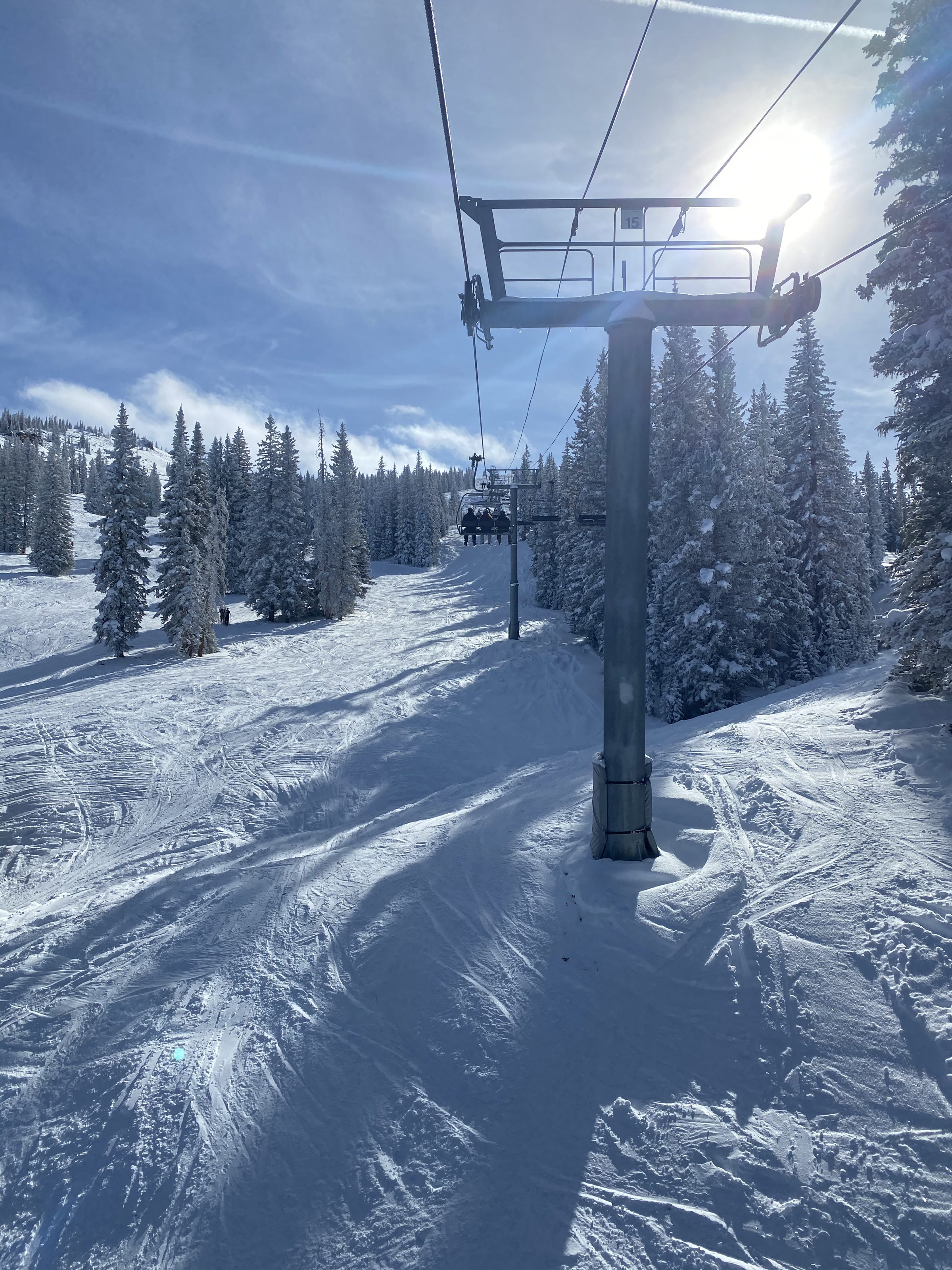 A chairlift rising through snow-covered pines on Aspen Mountain