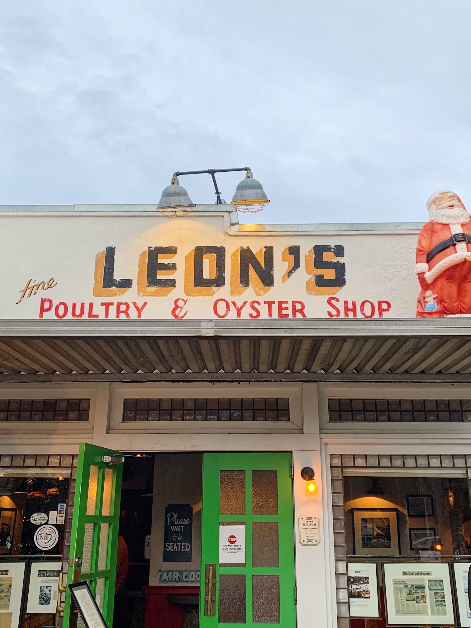 The hand-painted sign and green front doors of Leon's Fine Poultry & Oyster Shop, with a plastic Santa on the roof