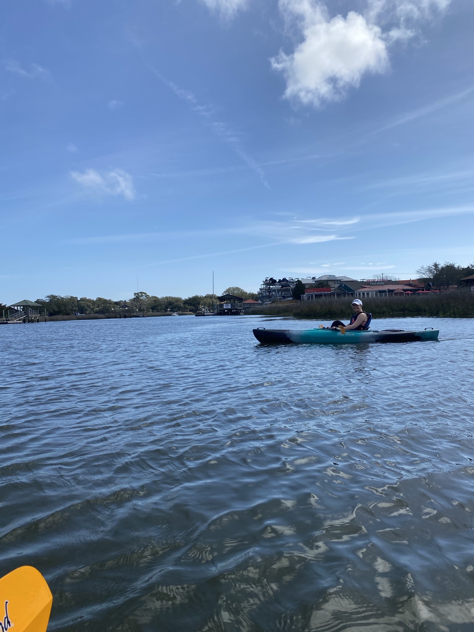 A kayaker on Shem Creek, with docks and restaurants along the bank