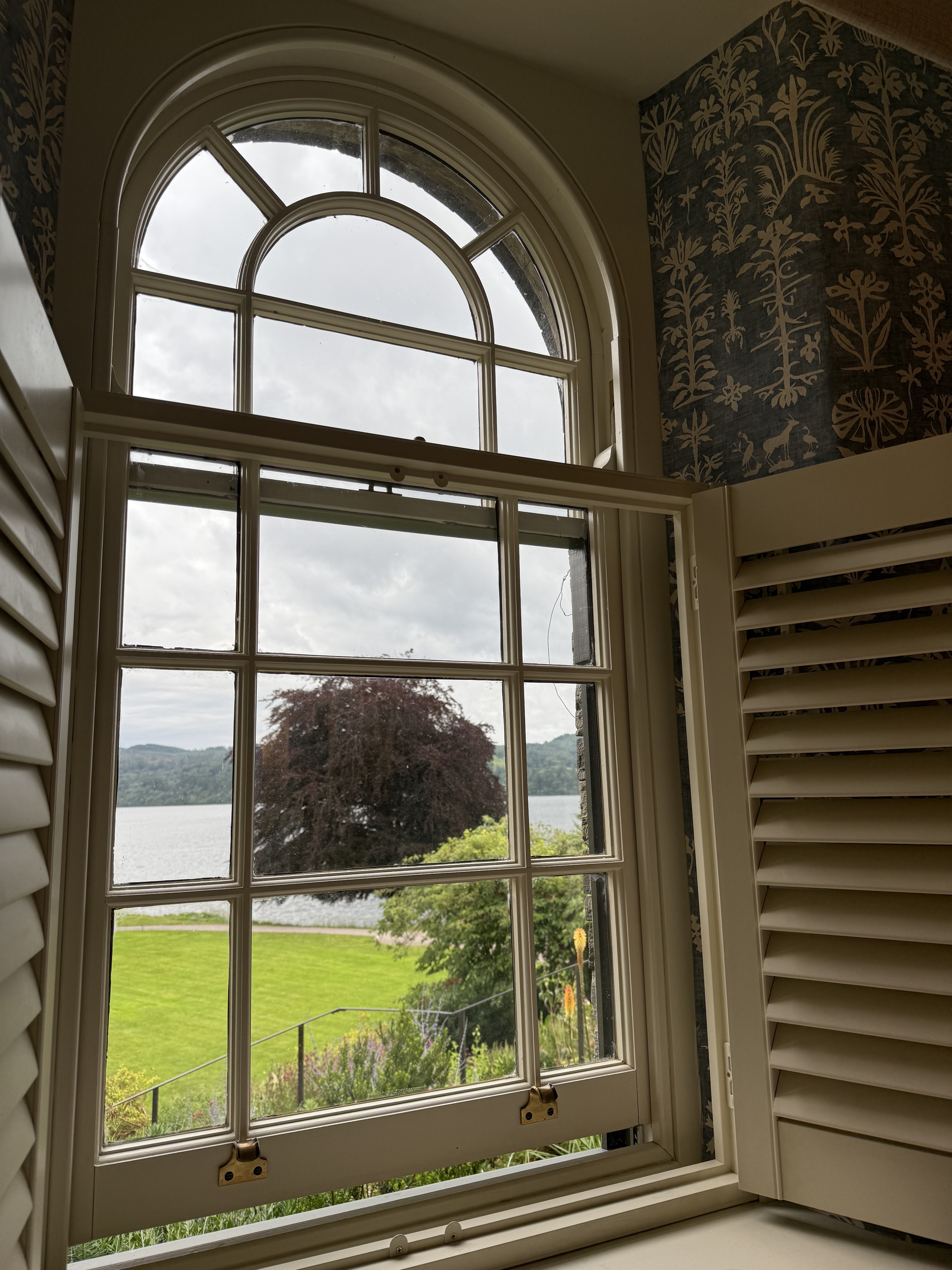 View of Lake Windermere through an arched window at Langdale Chase