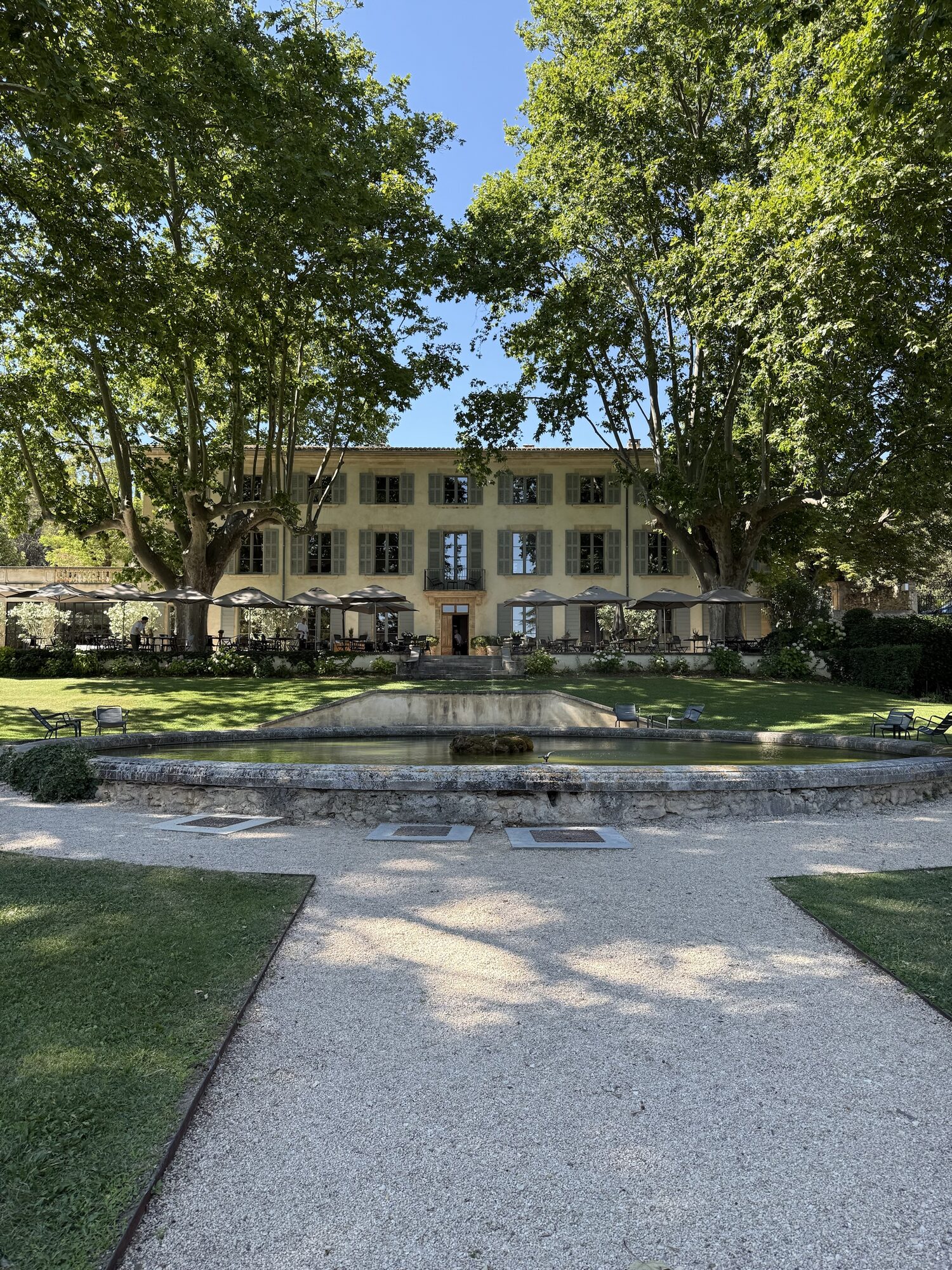 The main house at Domaine de Fontenille behind its round stone basin and plane trees