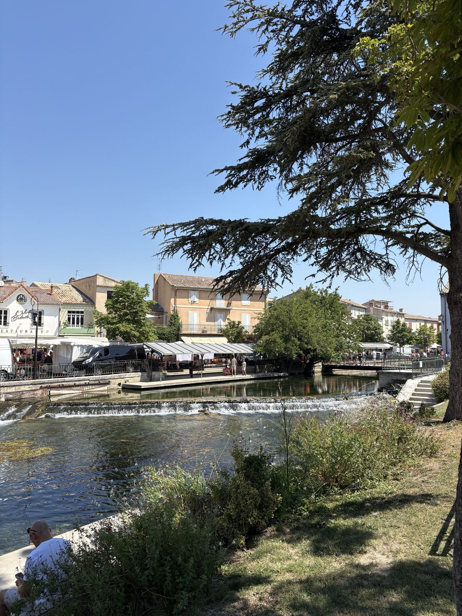 The River Sorgue running over a weir past market stalls in L'Isle-sur-la-Sorgue
